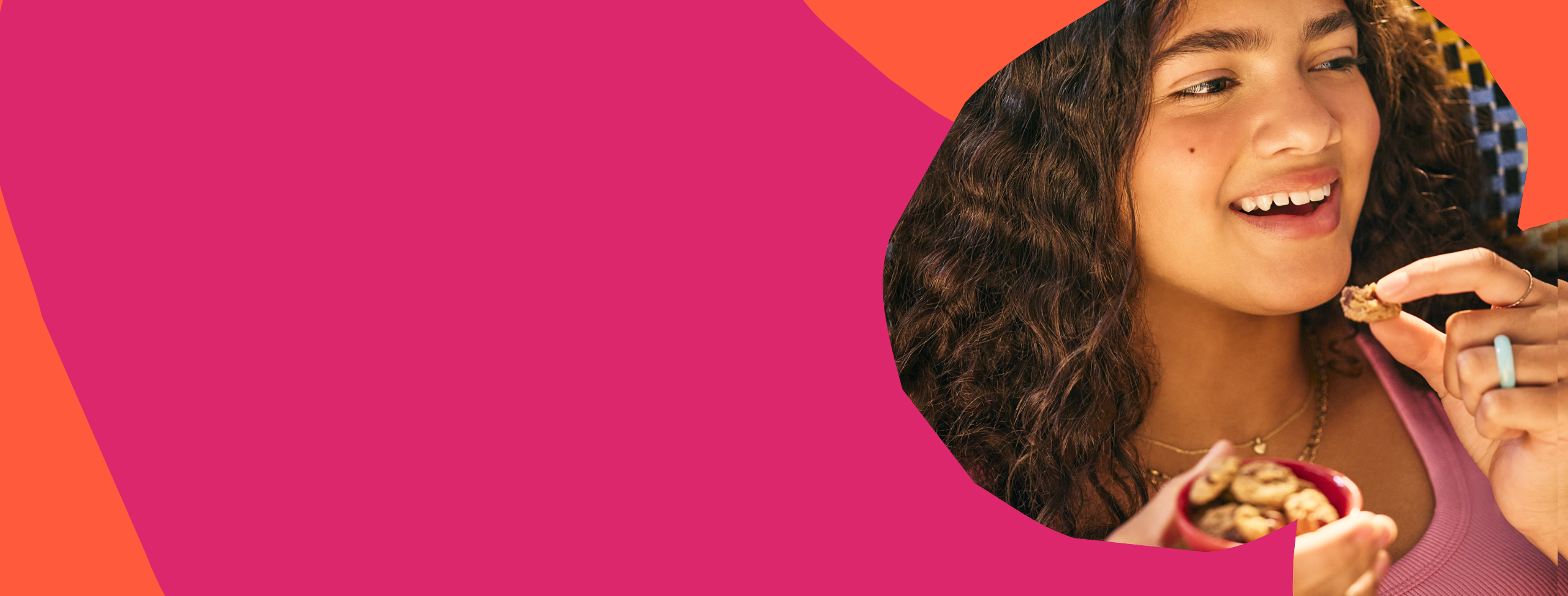 Girl eating MadeGood soft baked cookies on a pink and orange abstract background. Girl eating MadeGood soft baked cookies on a pink and orange abstract background.