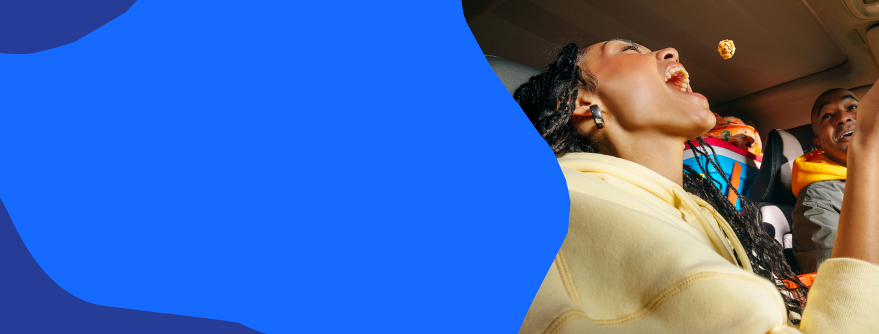 Woman eating popcorn in a car with a man beside her on a blue abstract background