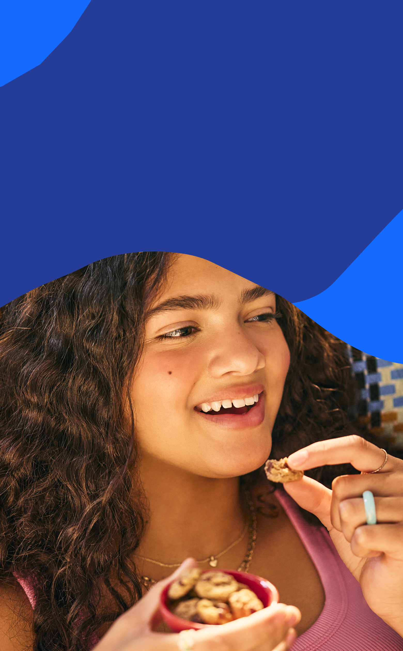 Woman eating MadeGood Cookies with a colorful background