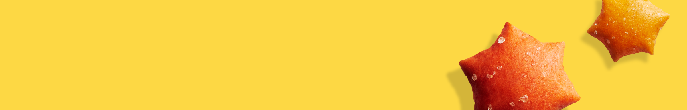 Two star-shaped, orange snacks with visible salt crystals are on a bright yellow background. The mood is vibrant and playful.