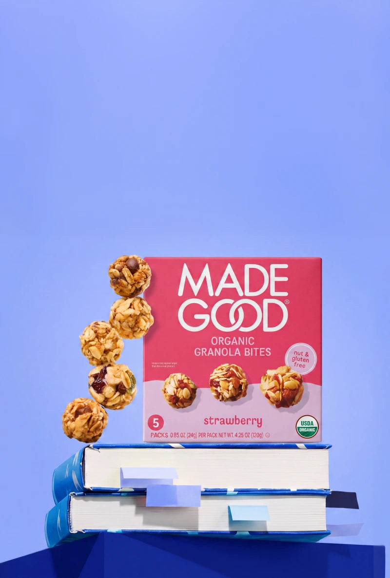 Background of blue abstract shapes, overlaid with scattered MadeGood granola bites.