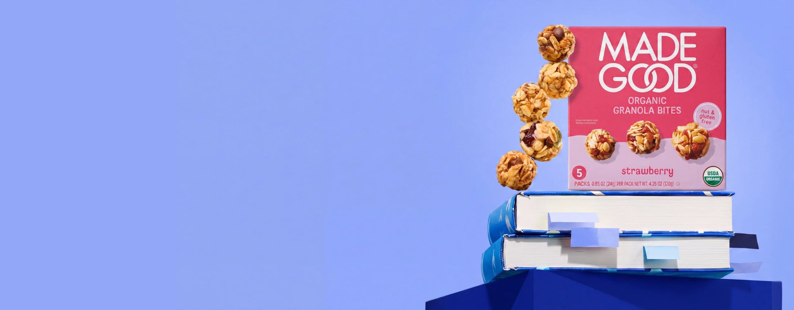 Background of blue abstract shapes, overlaid with scattered MadeGood granola bites.