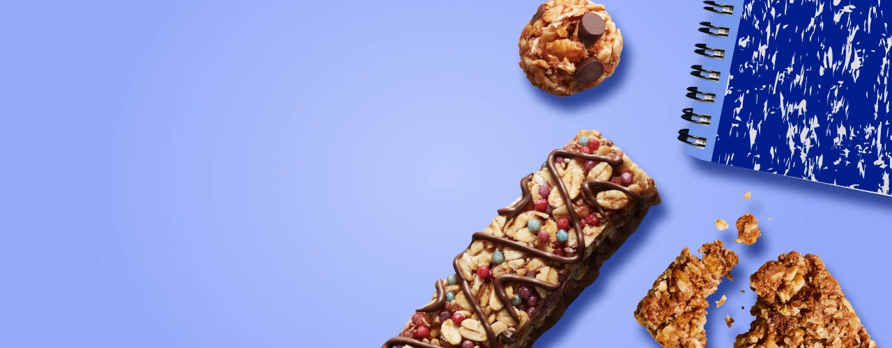 A MadeGood bar piece with oats and dark chocolate in it on a blue background