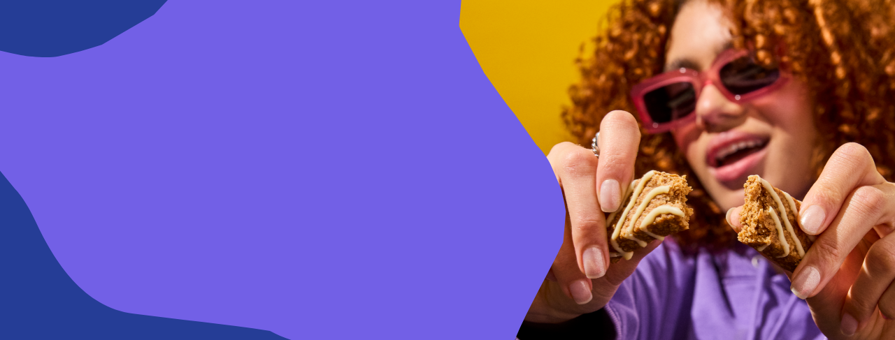 Woman holding two morning bars against a colorful abstract blue background.